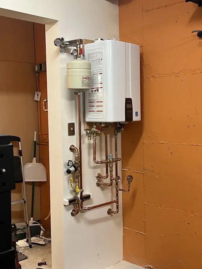 Plumbing technician inspecting water heater connections in Hazlet